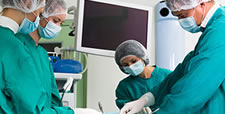 Doctors in operating room with monitor in background